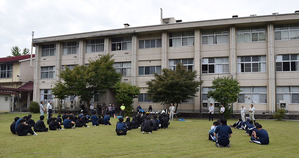 校庭で教員の話を聞く生徒の様子